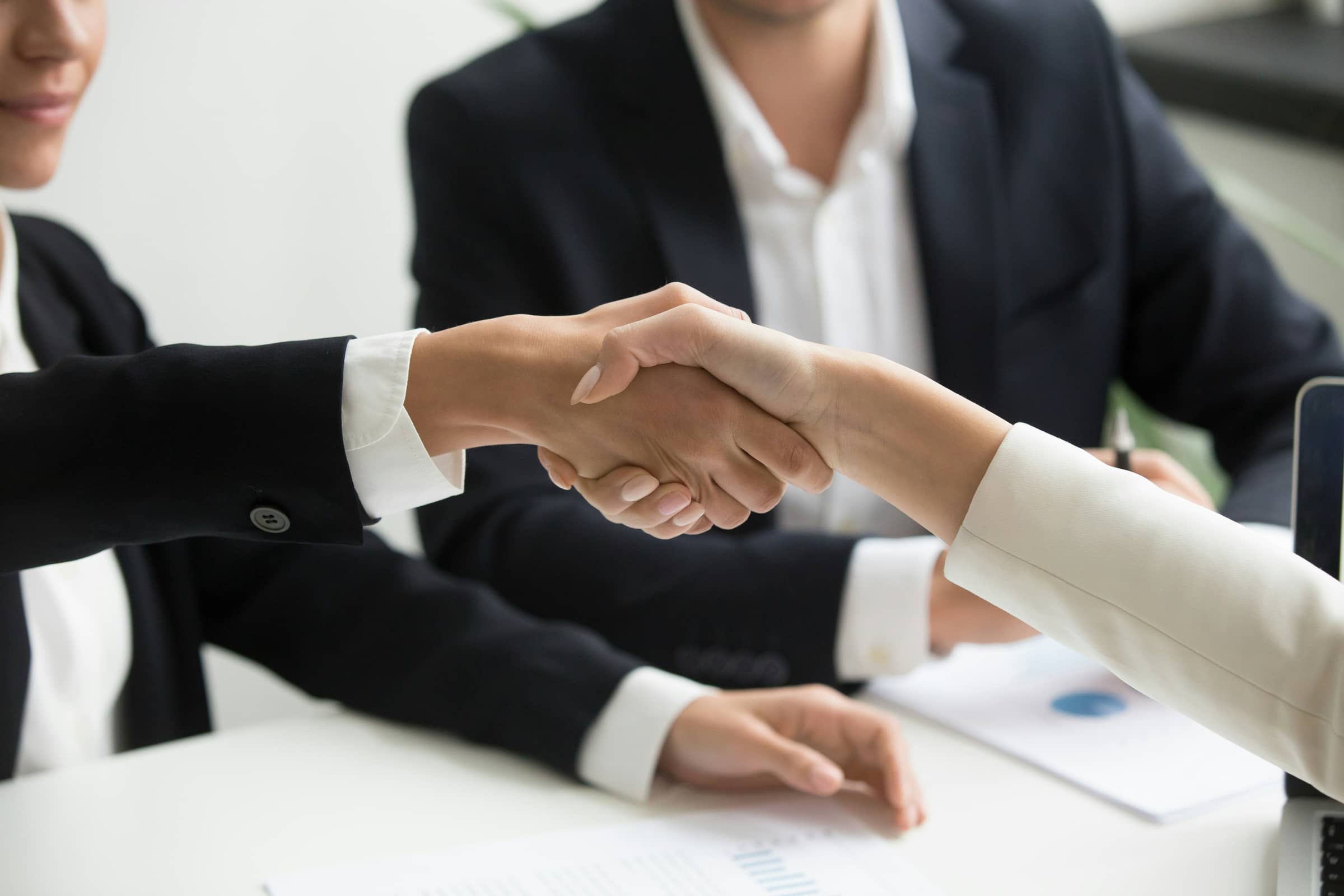 Two business people shaking hands over a laptop