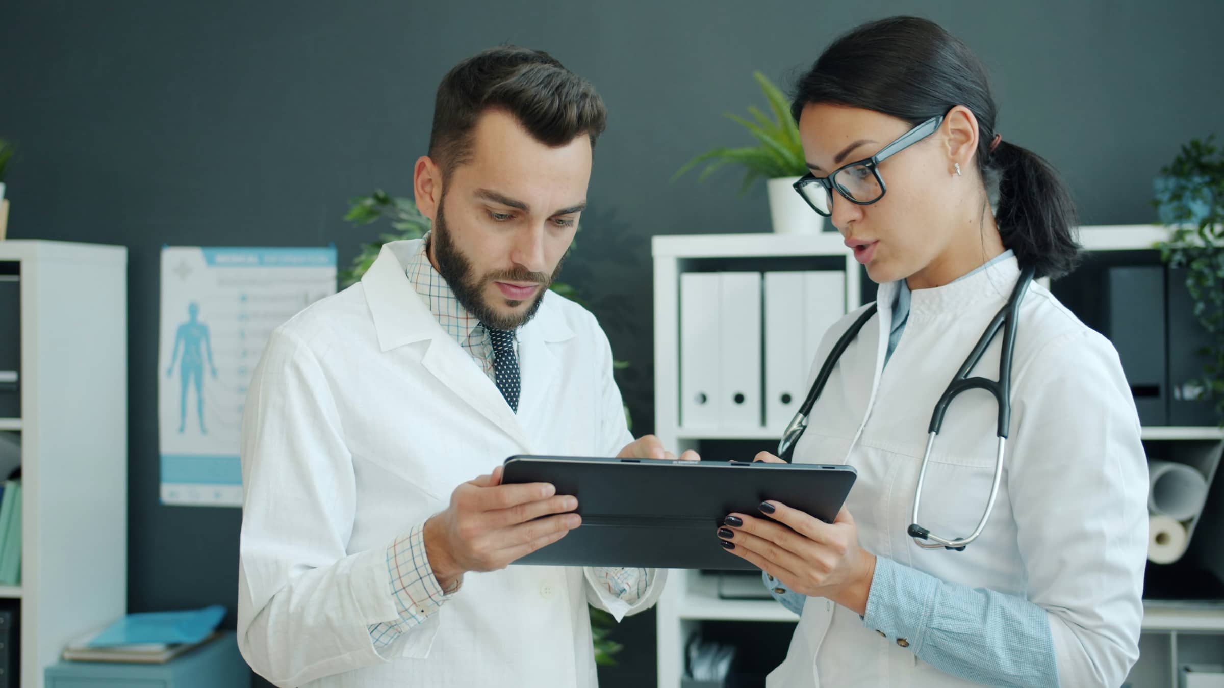 Tablet üzerinden kayıt inceleyen iki doktor